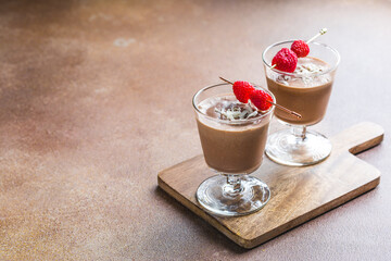 Chocolate dessert panna cotta with almond in glass jars on wooden background
