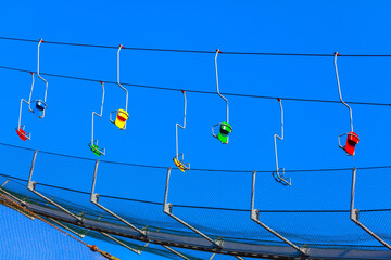 Colorful empty chairlifts suspended against a deep blue sky. A vibrant and dynamic composition...