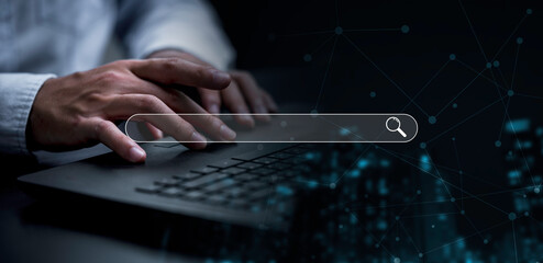 Businessman using computer laptop with search bar icon for browsing information network and SEO or...