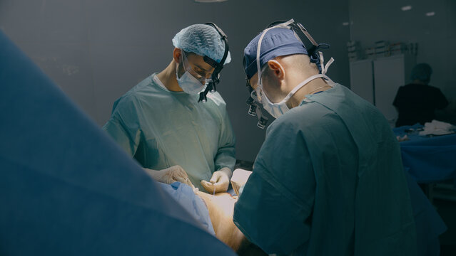 Medical team men doctors surgeons medics processing bariatric surgery stomach belly surgical operation with scalpel illness tumor sore emergency aid treatment hospital clinic health patient medicine