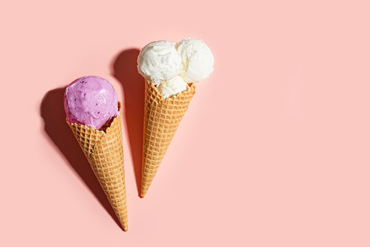Two crispy ice cream cones vanilla and blueberry flavors