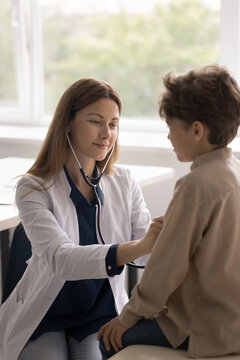 Cardiology checkup. Vertical shot friendly young woman doctor listen to little child patient heart with stethoscope hear lungs after recovery from bronchitis pneumonia on meeting at pediatric cabinet