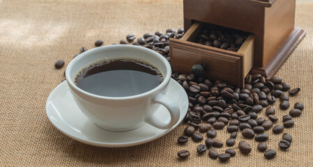 a cup of coffee with coffee beans scattered on the table	