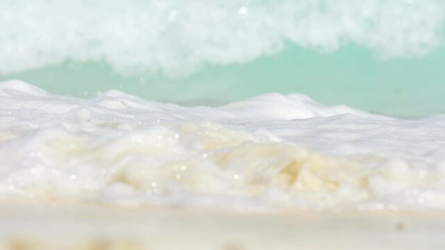 Drone view of beautiful seamless never ending footage while turquiose sea waves breaking on sandy coastline. Aerial shot of golden beach meeting deep blue ocean water and foamy waves