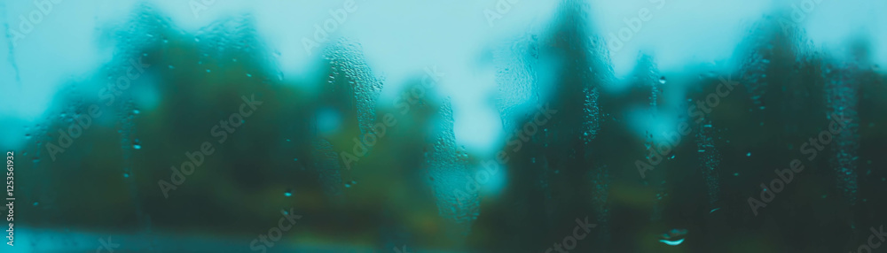 Aufkleber blurred view of a forest through a rain-streaked window with soft colors in the background