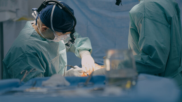 Group of surgeons men doctors physicians in medical masks process surgical operation trauma health treatment medicine aid plastic surgery with scalpel saving life patient in operating clinic hospital