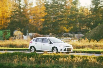 White hybrid car driving on rural road