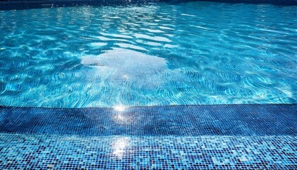 crystal clear blue swimming pool water background with ripples sunlight waves and mosaic tiles on floor in summer