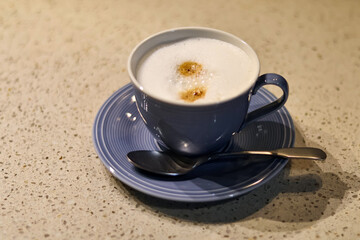fresh cappuccino or coffee with milk in a blue cup and teaspoon