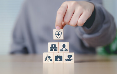 Health insurance and medical care concept. Woman placing wooden blocks with health-related icons,...