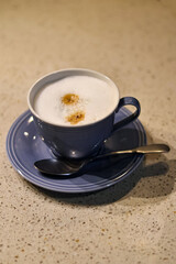 fresh cappuccino or coffee with milk in a blue cup and teaspoon