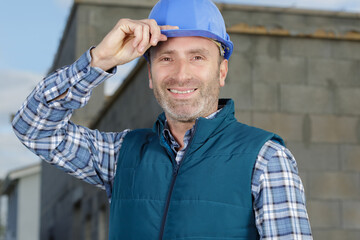 portrait of happy builder holding his helmet