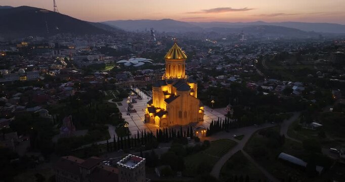 Drone shot of Sameba Cathedral, one of the most important symbols of Georgia. As the camera rotates, you can see this magnificent structure and the surrounding city of Tbilisi.