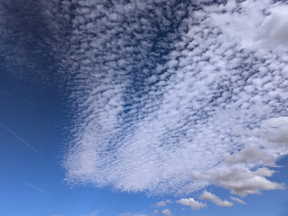 Striking mackerel sky with white altocumulus clouds and scattered lower clouds adding depth against...