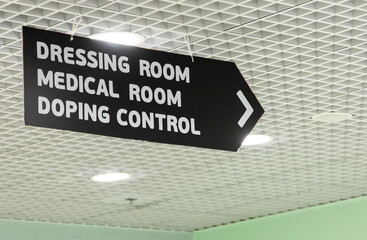 Sign directing visitors towards dressing room, medical room, and doping control area in a sports...