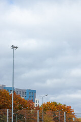 Autumn trees stand out against a cloudy sky near modern buildings in a residential area during late...