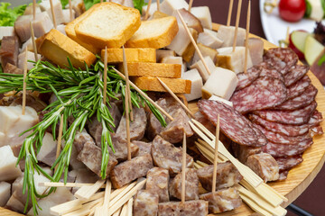 Charcuterie board featuring a variety of meats, cheeses, and bread garnished with fresh herbs at a gathering