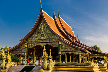 Fototapeta premium Background of the tourist attraction Wat Sirindhorn Wararam or the famous glowing temple in Thailand. Ubon Ratchathani is adjacent to Laos. Tourists always like to come to see the beauty at night.