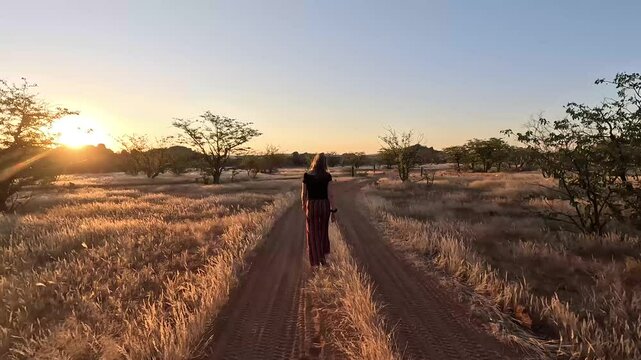 A girl walking on a road in Namibia towards the sunset