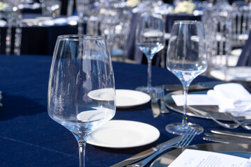 White flowers and glasses are placed on the event table. Cutlery is arranged neatly.