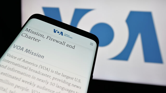 Stuttgart, Germany - 01-31-2025: Smartphone with website of US broadcasting network Voice of America (VOA) on screen in front of logo. Focus on top-left of phone display.