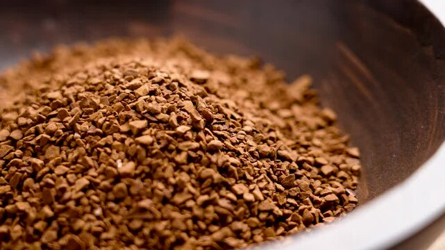 Granules of instant roasted caffeine-free coffee in wooden bowl. Unprocessed raw decaf drink ingredient. Front view. Rotation