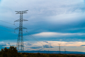 High voltage pylons in a field, on a winter morning with cloudy sky.