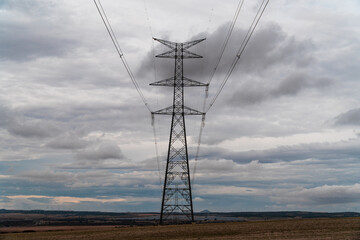 High voltage pylons in a field, on a winter morning with cloudy sky.
