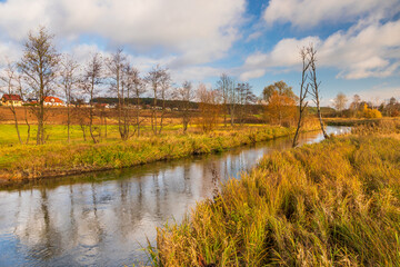 Fototapeta premium Radunia river flowing through the brown meadows. Kashubia, Pomerania, Poland.