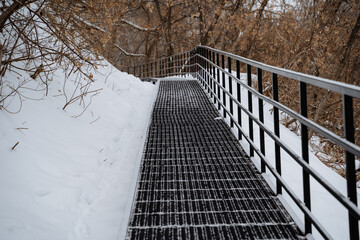 A metal bridge that features stairs meticulously leading into a beautifully picturesque snowy...