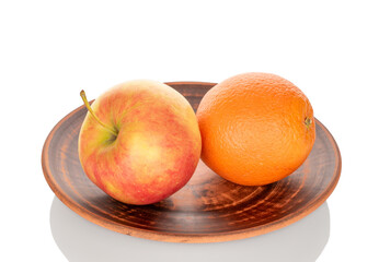 One juicy orange and apple on a clay plate, close-up, isolated on a white background.