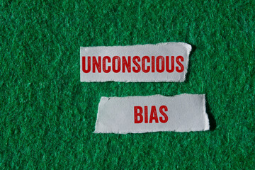 Unconscious bias message written on ripped torn paper pieces on green background. Conceptual...