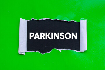 Parkinson message written on ripped torn green paper on black background. Conceptual parkinson symbol. Copy space.