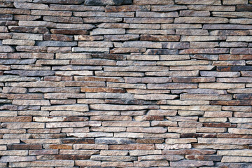 Wall of cut natural stone. Flat cut natural stone art arranged neatly or randomly on building walls and facades.