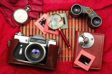 Outfits and accessories of hipster on wooden background.Adventure and wanderlust journey concept image with travel items like SLR camera,magnifier,gloves,slides and binocular.Top view.