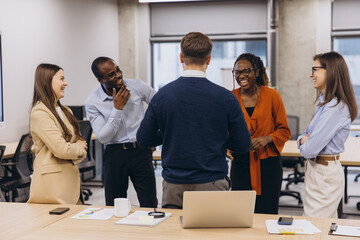 Diverse colleagues enjoying a lighthearted moment during a productive workday, fostering a positive...