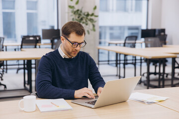 Obraz premium Professional working on laptop at sleek office desk, focusing on screen while typing