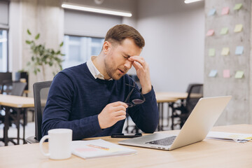 Office worker experiencing eye strain, massaging tired eyes and pausing during workday