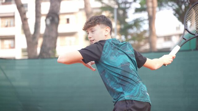 A cute sporty tennis player male child plays a forehand tennis shot. Teenager.