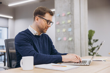 Professional businessman working intently on laptop, displaying concentrated effort within sleek...