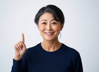 Asian mature female smiling and gesturing with raised finger on white background