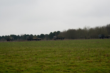 convoy of British army MAN HX & SV Heavy Utility Trucks driving along a dirt track road