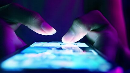 Finger of woman touching scroll page app on mobile phone.In a room with blue and purple neon tones.concept Social media and marketing, viral video - Powered by Adobe