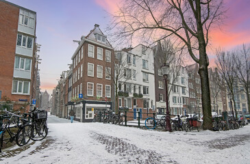Snowy city Amsterdam in the Netherlands in winter at sunset
