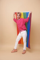Youth asian transgender LGBT with Rainbow flag isolated over nude color background. Man with a gay pride flag concept.