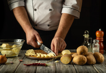 A skilled chef engages in culinary preparation, chopping fresh potatoes with precision. Various ingredients are arranged artistically on a wooden countertop, blending rustic charm and gastronomy