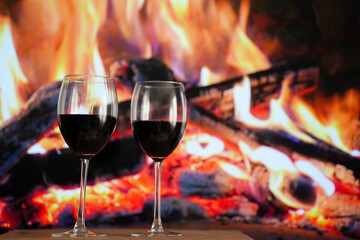Pair of red wine glasses against the fire.