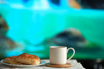 Tea cup and plate with pastries on a beautiful turquoise background.