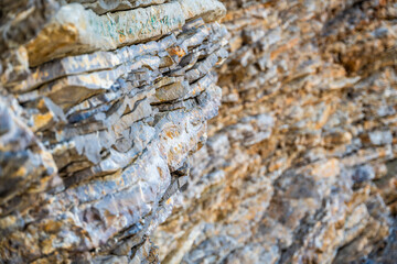 Layered rock texture in Budva, Montenegro. Sedimentary rocks with rugged surface of gray and brown. Natural formation of layers and cracks, geological structure.