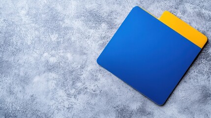 A vibrant blue and yellow folder rests on a textured gray surface, showcasing a minimalist design ideal for organizing documents.